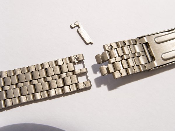 Bracelet en métal ouvert, l’agrafe retirée posée à côté